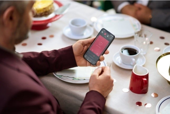 A man holds his cell phone at dinner