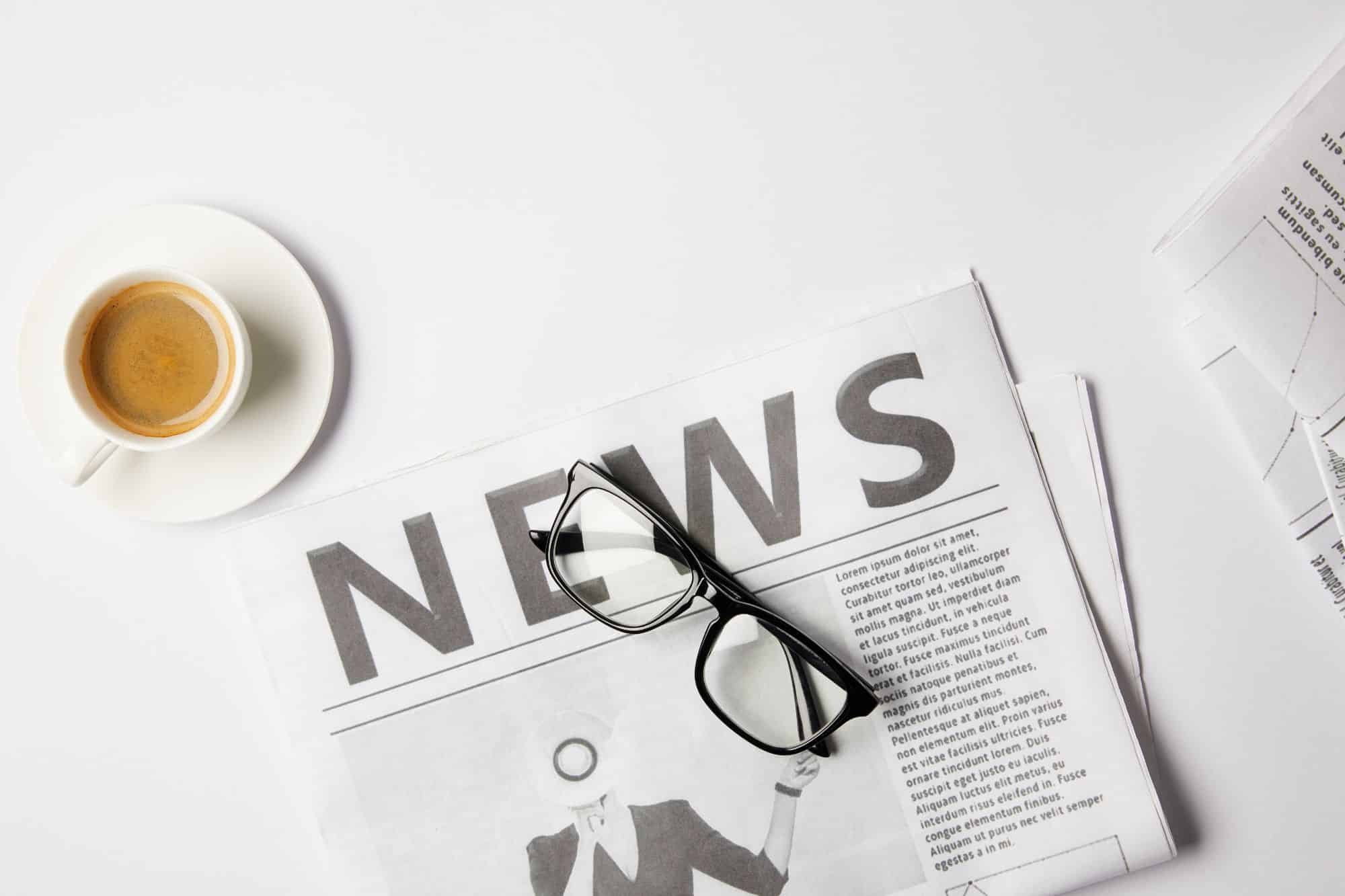 a newspaper under a coffee cup and glasses