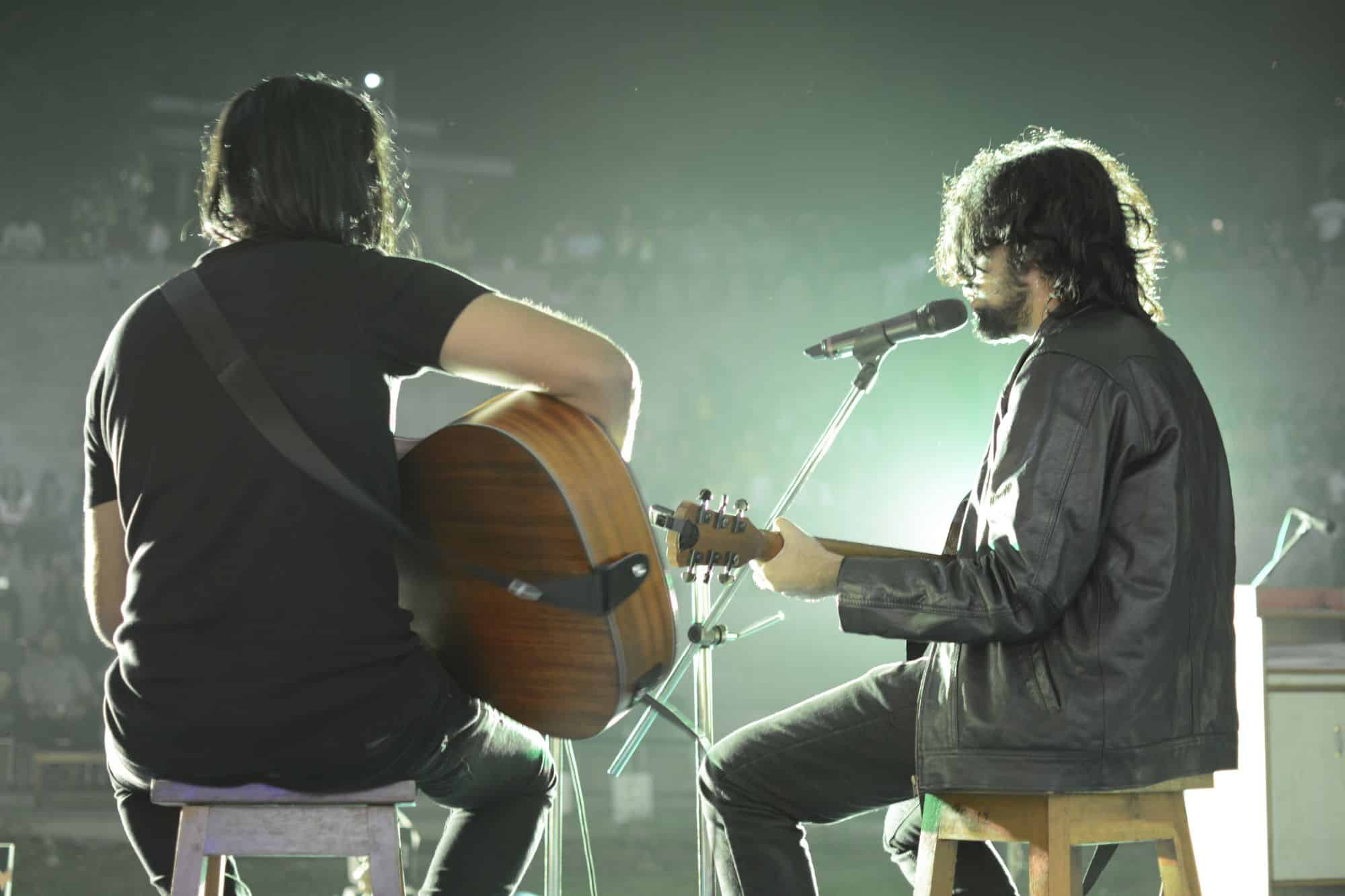 two men playing guitar and singing