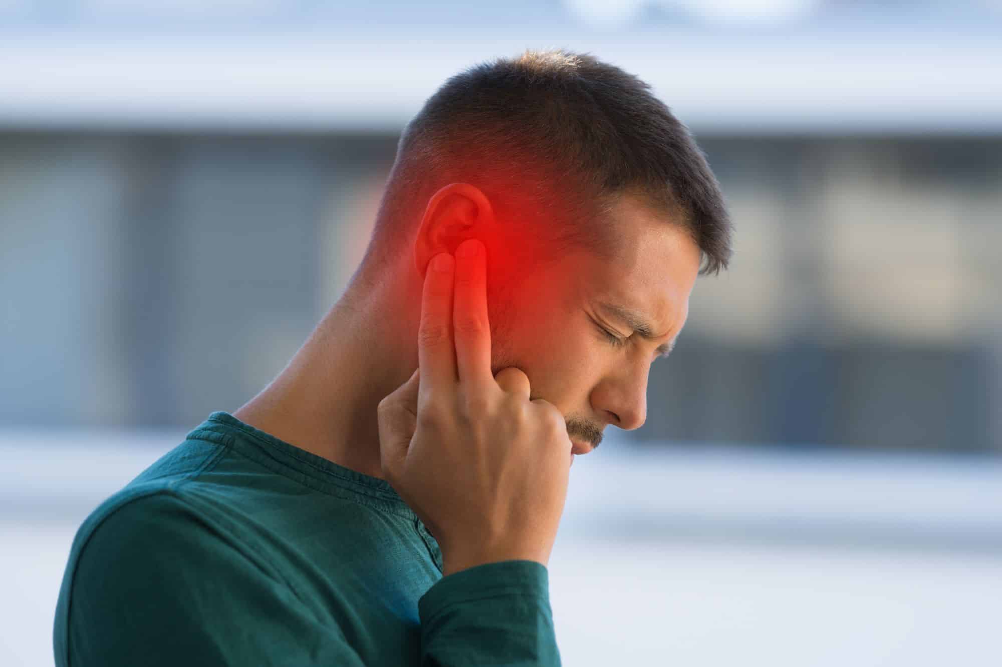 a man holding his ear which is glowing red to indicate pain