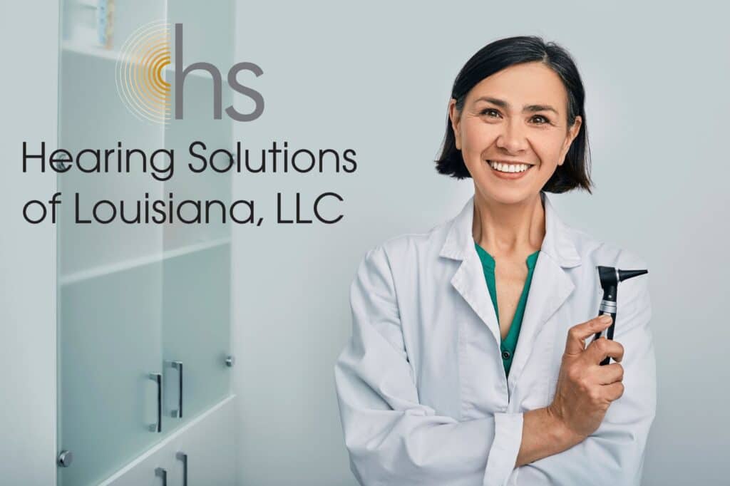 smiling audiologist holding an otoscope